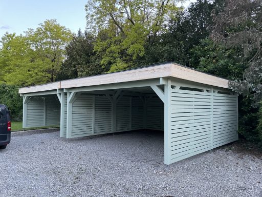 Parkanlage mit überdachten Stellplätzen und hellgrünen Wänden aus Holz.